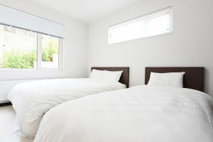 two beds in a white bedroom with two windows at Sapporo - House - Vacation STAY 14578 in Sapporo