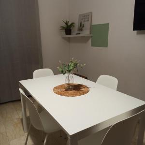 une table blanche avec des chaises et un vase de fleurs. dans l'établissement Casa vacanza Melf, à Terrasini