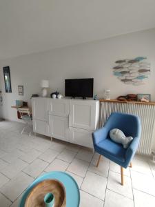a living room with a blue chair and a tv at Studio Golfe Juan, plages, parking, climatisation in Vallauris