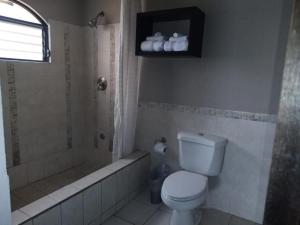 y baño con aseo, ducha y bañera. en L´Aurora Inn hostal en Guatemala