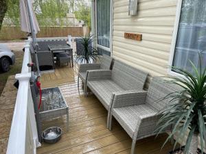 a porch with two wicker chairs and a grill at Luxury Holiday Home Happiness at Tattershall lake# in Tattershall