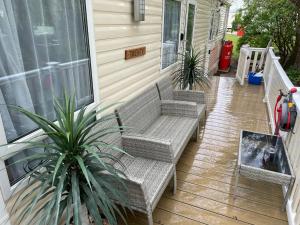 une terrasse couverte avec 2 bancs en osier sur une maison dans l'établissement Luxury Holiday Home Happiness at Tattershall lake#, à Tattershall