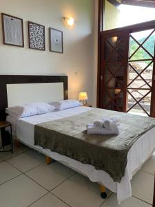 a bedroom with a large bed with towels on it at Casa H11 em condomínio fechado frente a praia Maresias in São Sebastião