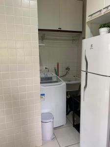 a kitchen with a white refrigerator and a sink at Casa H11 em condomínio fechado frente a praia Maresias in São Sebastião