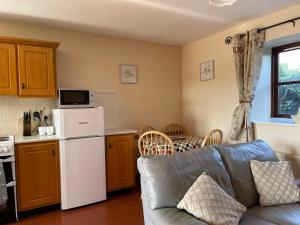 a living room with a couch and a kitchen at Coningbeg Cottage in Kilmore Quay