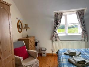 a bedroom with a bed and a window and a chair at Coningbeg Cottage in Kilmore Quay