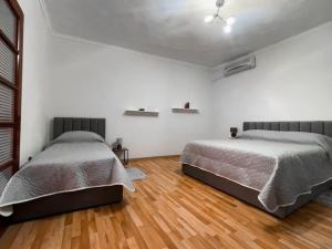 Habitación blanca con 2 camas y suelo de madera. en Vila Kodra en Tirana