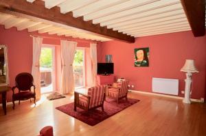 un soggiorno con pareti rosse, tavolo e sedie di Le Moulin des Poètes 