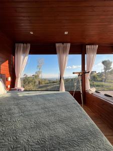 - une chambre avec un lit et une grande fenêtre dans l'établissement Cabanas Românticas em meio a Natureza - Anitápolis/SC - CB05, à Annitapolis
