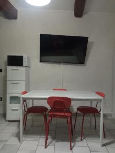 mesa blanca con sillas rojas y TV en la pared en Studio tout confort en Provence Mont Ventoux., en Bédoin