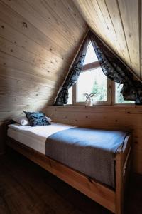 Cama en habitación de madera con ventana en Obrochtowa Chata en Kościelisko