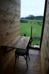a wooden table and chair in a room with a window at Habitación cálida y acogedora a pasos del mar in Buchupureo