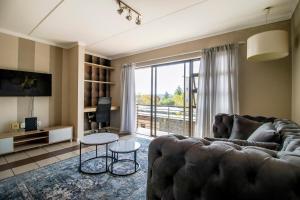 a living room with a couch and a large window at Tripleg Apartments 1 in Fourways