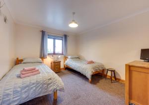 a bedroom with two beds and a tv at Y Beudy in Y Felinheli