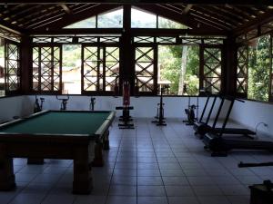 a pool table in a room with windows at Casa H11 em condomínio fechado frente a praia Maresias in São Sebastião