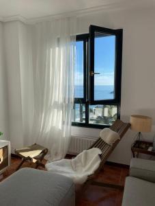 uma sala de estar com um sofá e uma janela em Bonito dúplex con vistas al mar em Comillas