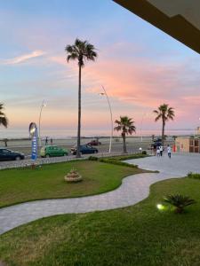 um parque perto da praia com palmeiras e o oceano em AMWAJ HOTEL em El Jadida