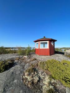 una piccola casa rossa sulle rocce nel deserto di Klobbars Gästhem o Stugor a Kökar