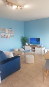 a living room with a tv and tables and chairs at La MAISON BLEUE, Smeg Bleu azur in Évian-les-Bains