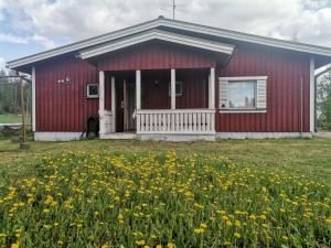 a red house with a field of flowers in front of it at DecaVillage Studios in Kuivanto