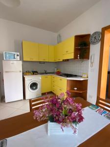 una cucina con armadi gialli e un tavolo con fiori di Il Profumo dei Tigli a Imola