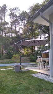 un patio con mesa y sombrilla en Maison Solyselva Piscine- Proche océan- Climatisée en Saubion