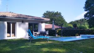 a backyard with a pool and a table and chairs at Maison Solyselva Piscine- Proche océan- Climatisée in Saubion