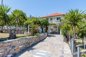 a house with a stone wall and palm trees at Margini's Country House in Panormos Skopelos