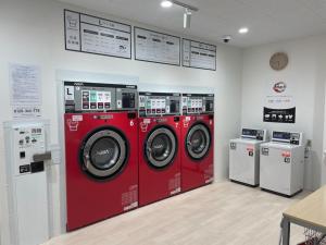 vier rote Waschmaschinen in einer Waschküche in der Unterkunft Tennen Onsen Kakenagashi no Yado Hotel Pony Onsen - Vacation STAY 50911v in Towada