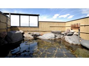 un estanque con rocas frente a un edificio en Tennen Onsen Kakenagashi no Yado Hotel Pony Onsen - Vacation STAY 50916v, en Towada