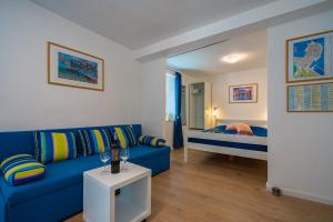 a living room with a blue couch and a bed at Apartment Rose in Korčula