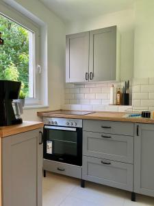 a kitchen with white cabinets and a black oven at Sali - R1 - Apartmenthaus, WLAN, TV in Remscheid