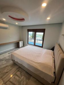 a bedroom with a large bed and a window at Denizolgun Homes Eska Villa 1+1 in Dalaman