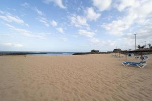 Dos sillas y una sombrilla en una playa de arena en SUN BAY, en Caleta de Fuste