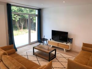 Una sala de estar con un sofá y un televisor. en Modern House next Disneyland, en Esbly