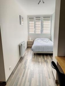 - une chambre avec un lit et du parquet dans l'établissement Le Jeanne, à Compiègne