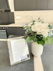 eine Vase voller weißer Rosen auf einem Tisch in der Unterkunft Le Jeanne in Compiègne