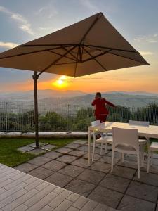 a woman standing under an umbrella over a table and chairs at Alba - Le Grotte Rooms & Apartments in Camerano