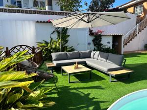 un patio con sofá y sombrilla en Casa con piscina y jardín con vistas al mar, en Puerto de la Madera