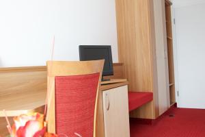 Camera dotata di scrivania con computer e sedia rossa. di Gästehaus am Rastberg a Langenbach