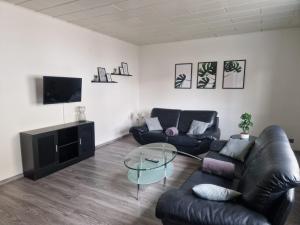 ein Wohnzimmer mit 2 Ledersofas und einem Glastisch in der Unterkunft Ferienwohnung am See in Borken