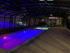 a large swimming pool with purple lighting in a building at Domki Wakacyjne by LIDER in Łeba