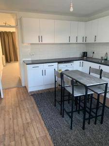 a kitchen with a table and chairs and white cabinets at Beautiful-2 bedroom Apartment, 1 bathroom, sleeps 6, in greater london (South Croydon). Provides accommodation with WiFi, 3 minutes Walk from Purley Oak Station and 10mins drive to East Croydon Station in Purley