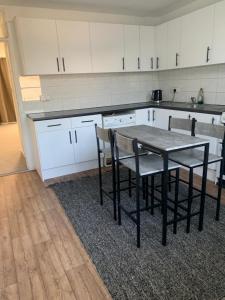 una cucina con tavolo, sedie e armadietti bianchi di Beautiful-2 bedroom Apartment, 1 bathroom, sleeps 6, in greater london (South Croydon). Provides accommodation with WiFi, 3 minutes Walk from Purley Oak Station and 10mins drive to East Croydon Station a Purley