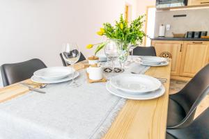 einen Esstisch mit weißen Tellern und Weingläsern in der Unterkunft Czarna Góra Apartamenty TATRY GÓRY BIAŁKA T BUKOWINA T ZAKOPANE in Czarna Góra