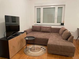 a living room with a brown couch and a tv at Mely Rose in Ljubljana