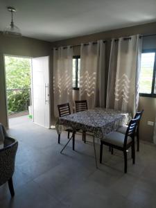 a dining room with a table and chairs and windows at ACHALAY, Alquileres temporarios Catamarca. DPTOS CENTRICOS HERMOSOS in San Fernando del Valle de Catamarca
