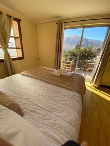 um quarto com uma cama grande e uma janela grande em Cabañas & Spa Qamawi em Pan de Azúcar