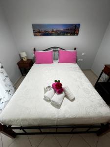 a bed with pink and white towels and pink pillows at Anna's Apartments in Nikiana
