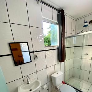 uma casa de banho com um WC, um lavatório e uma janela em La Casita Hostel PF na Praia do Forte